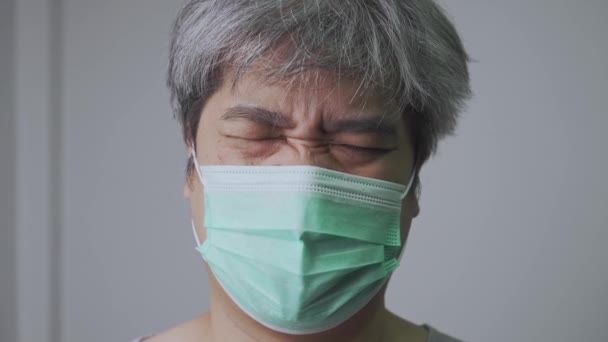 医者の顔のマスクをしたアジア系の病気の男と頭の中で頭痛を保持するために手を取ります.パンデミックコロナウイルスと呼吸器疾患の保護の概念 — ストック動画