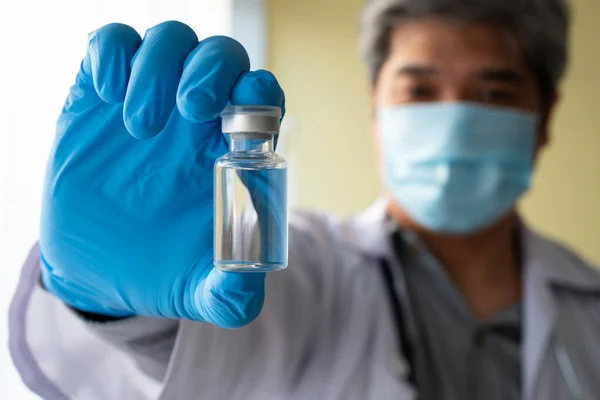 アジアの男性医師は 患者の抗体サンプルを研究し 分析するために 19のコロナウイルスワクチンを採用した医療用手袋とフェイスマスク保持注射器を着用しています 医療の概念 — ストック写真