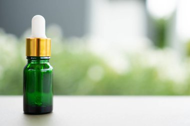 Masanın üzerinde damlatan yeşil bir cam şişe. Aroma yağı, kozmetik ve güzellik kavramı.