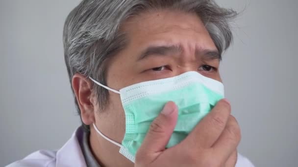 Un asiatic bolnav purtând o mască de faţă medicală şi tuse şi acoperindu-şi gura cu mâna mea. Conceptul de protecție a coronavirusului pandemic și a bolilor respiratorii — Videoclip de stoc