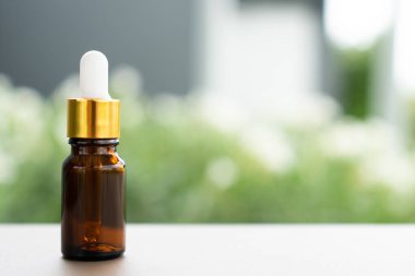 Masanın üzerinde damlatan kahverengi bir cam şişe. Aroma yağı, kozmetik ve güzellik kavramı.