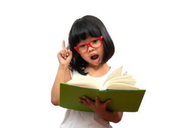 Kırmızı gözlüklü mutlu Asyalı küçük anaokulu kızı yeşil bir kitap tutuyor ve beyaz soyutlanmış arka planda başparmak kaldırıyor. Okul çocuğu kavramı ve ilköğretim ve anaokulu, ev okulu