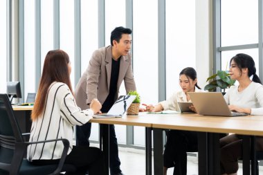 Bir grup profesyonel modern bir ofiste ortak bir toplantıya katılıyor. Sahne, üretken bir kurumsal ortamda takım çalışması, liderlik ve dinamik iletişimi vurguluyor.