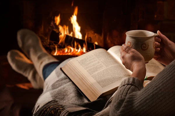 Mujer lee libro cerca de la chimenea — Foto de Stock