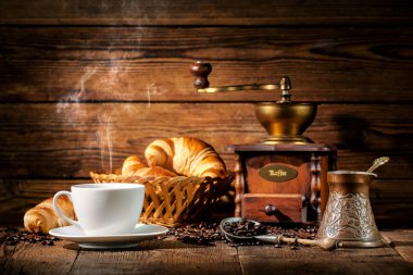 Ahşap arka planda kahve ve kruvasan.