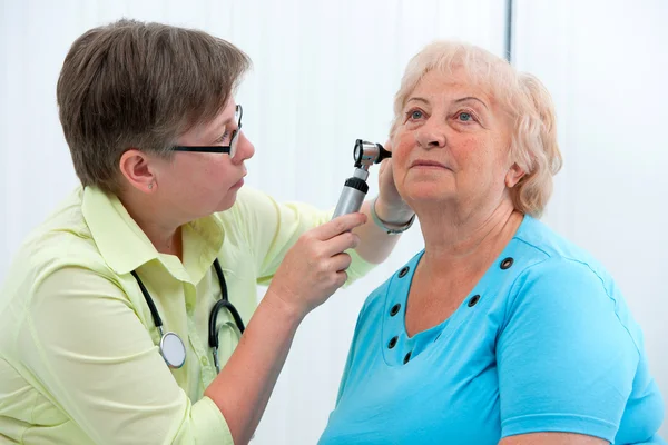 Ein Arzt schaut mit einem Instrument ins Ohr des Patienten — Stockfoto