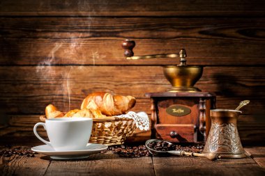 Ahşap arka planda kahve ve kruvasan.