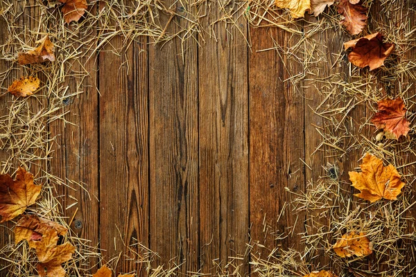 Daun musim gugur dan jerami pada latar belakang kayu — Stok Foto