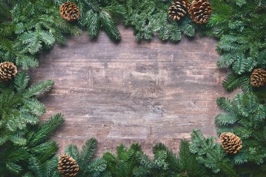 Noel ve Yeni Yıl arkaplanda köknar dalları ve ahşap tahtada çobanpüskülü