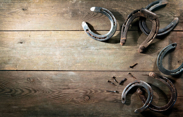 Old rusty horse shoes lying on a wooden barn floor