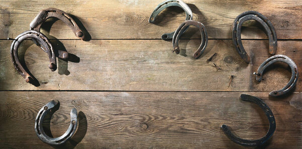 Old rusty horse shoes lying on a wooden barn floor