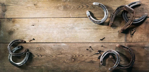 木製の納屋の床に横たわっている古い錆びた馬の靴 — ストック写真