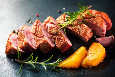 Biberiye ve baharatla süslenmiş dilimlenmiş ördek göğsü filetosunu kapat.