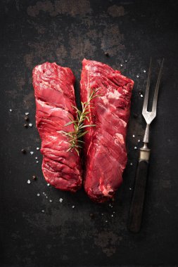 İki çiğ askı bifteği, ayrıca kasap bifteği olarak da bilinir ya da arka planda biberiye, biber ve tuz ile fileto asılır.