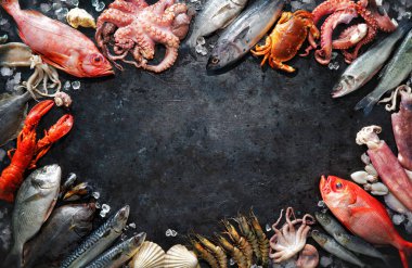 Koyu taştan arka planda taze balık ve deniz ürünleri çeşitleri. Üst görünüm