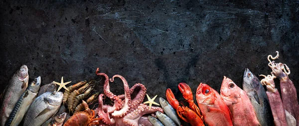 在深色石质背景下的新鲜鱼和海鲜的分类 顶部视图 — 图库照片