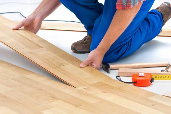 Homem que estabelece piso laminado — Fotografia de Stock