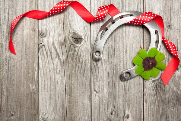 Hufeisen, Shamrock und rotes Band auf altem Holz — Stockfoto