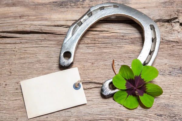 Horseshoe and four leaf clover with empty tag — Stock Photo, Image