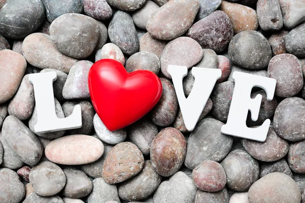 A palavra Amor com coração vermelho em pedras de seixos — Fotografia de Stock