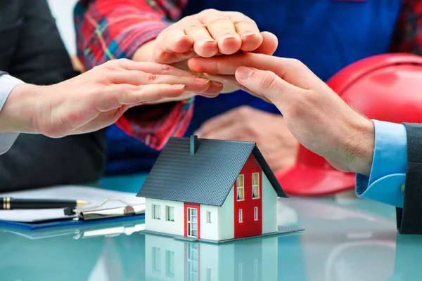 Manos salvando pequeña casa con un techo — Foto de Stock