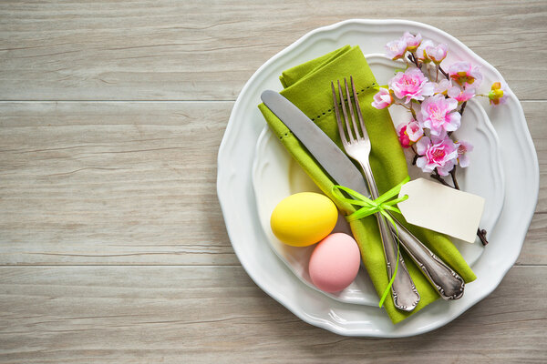 Накрытие пасхального стола с весенними цветами и столовыми приборами
