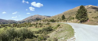 San Franco zirvesinin yeşil yamaçlarında uzanan dağ yolu manzarası, doğudan parlak bir ışık ile çekilen L 'Aquila, Abruzzo, İtalya