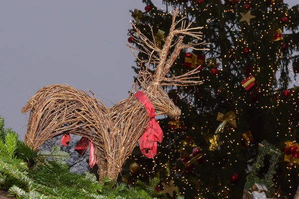 Christmas tree and wicker reindeer on stall roof at Xmas market — Stock Photo, Image