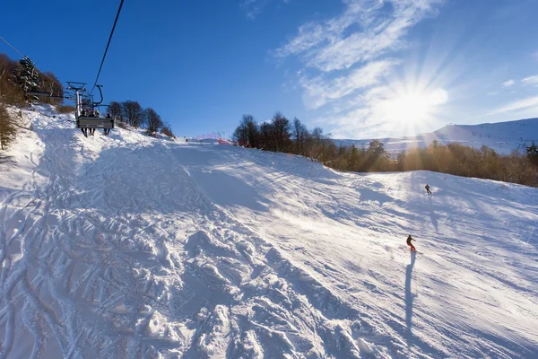 Ski lift over slopes in mountain with paths from skies and snowboards — Stock Photo, Image