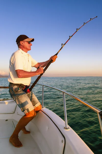 Angler fisherman fighting big fish on the ocean from the boat — Stock Photo, Image