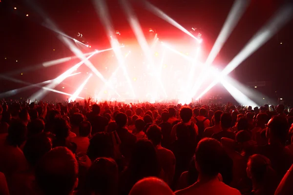 Genç insanların önünde parlak sahne ışıkları, kalabalık konser — Stok fotoğraf