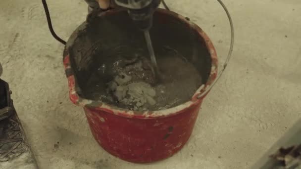 Het mengen van cement mortel in een emmer met een mixer — Stockvideo