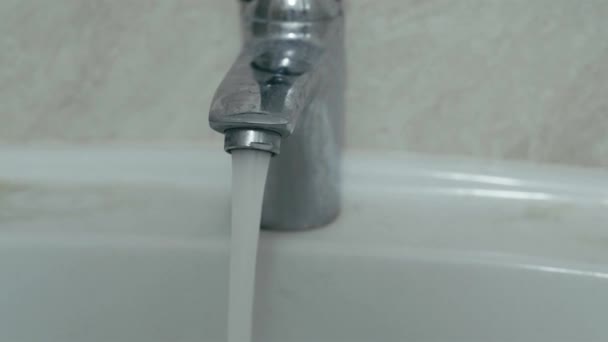 Een waterstraal stroomt uit een open kraan in de wastafel van de badkamer — Stockvideo