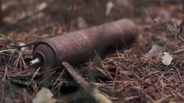 Een spuitbus ligt op de grond in een roestig bos — Stockvideo