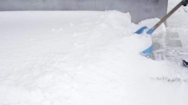 Sneeuw verwijderen rond het huis met een blauwe schop in slow motion — Stockvideo