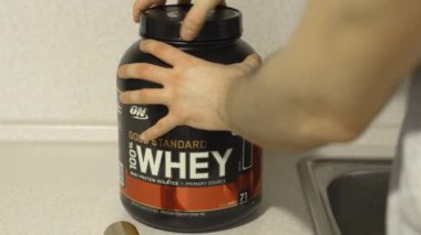 Kiev, Ukrayna-14 Şubat 2021: Bir kutu beyaz altın standart proteini açmak ve bir kepçe suda çözünen proteinle ayarlamak