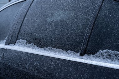 Arabadaki yolcu penceresinin çerçevesi kış sabahı buzla kaplıdır.