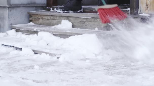 Kiev, Ukraine - 14 février 2021 : un homme balaie les marches en bois sur le porche de la neige lors d'une chute de neige en hiver — Video