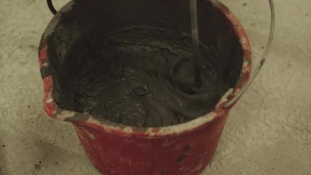 Het mengen van cement mortel in een emmer met een mixer — Stockvideo