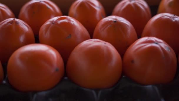 Fly over a box in fresh ripe persimmons of vibrant orange color — Stock Video