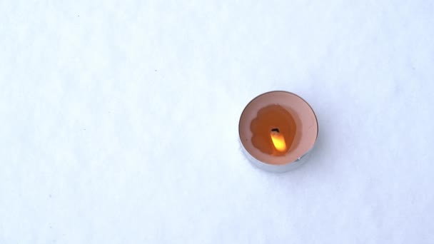 Свеча в жестяной банке горит в снегу зимой, крупным планом, вид сверху, Расположение в третьих и копировальное пространство — стоковое видео