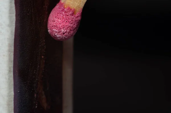 Friction of a match with a pink head on the rough material of a matchbox close-up, macro