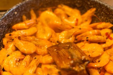 Yemek pişirirken tavadaki karidesi karıştır