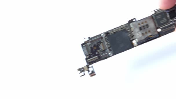 Kiev, Ukraine - March 11, 2021: hand puts the electronic circuit board iphone se apple with processor A9 on a white background close-up — Stok Video