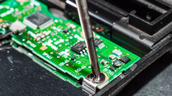 The process of replacing the green electronic board with a screwdriver