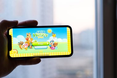 Kiev, Ukrayna - 2 Nisan 2021: Çiftlik kahramanları destanı şehir merkezinin arka planına karşı telefonda açıldı