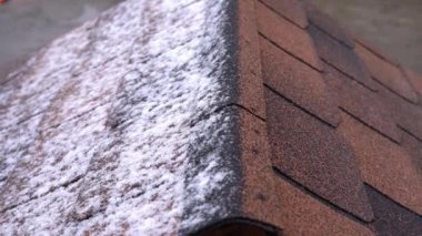 Çatının yarısı karla kaplı, üst tarafı manzaralı. Çatıya kar yağıyor.