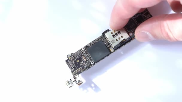 Kiev, Ukraine - March 11, 2021: Examination of electronic circuit board apple iphone se with A9 processor close up on white background — Stock Video