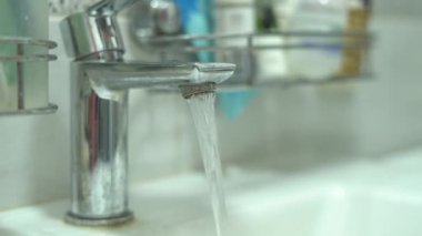 Lavabodaki musluğu açıp kapatmaya yakın çekim. Su basıncı ve saflığı