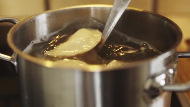 Смешивание пельмени с картошкой с ложкой в кастрюле с горячей водой — стоковое видео